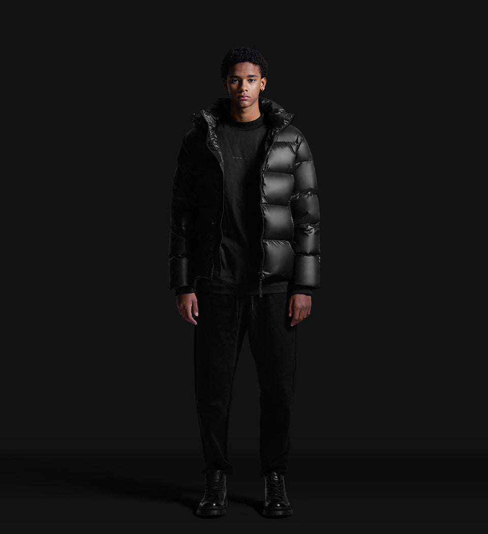 young man wearing waist-length black winter puffer jacket unzipped facing front